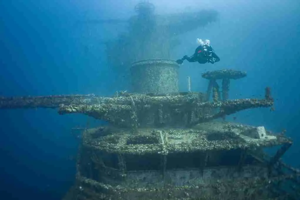 scuba diver swimming past a shipwreck